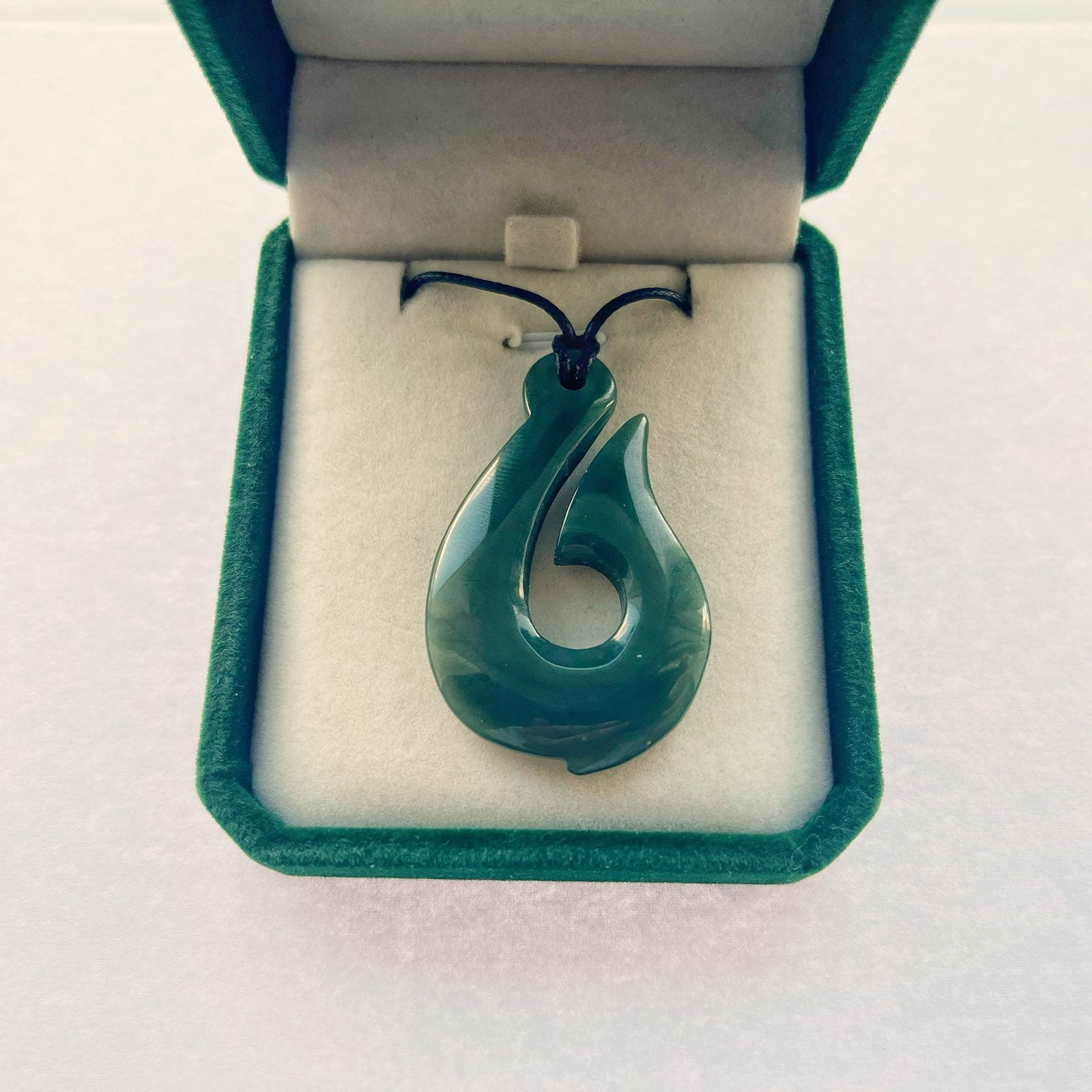 Greenstone hook pendant displayed in green velvet gift box